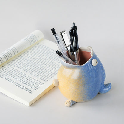 Ceramic pen holder placed on desk with pens inside 